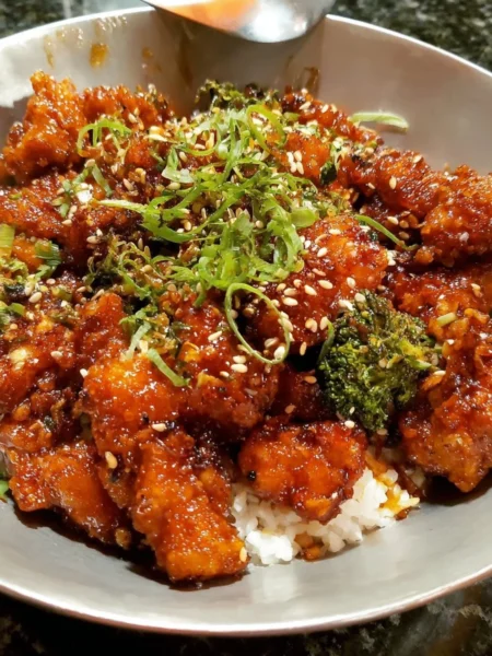 Crispy orange garlic chicken garnished with fresh herbs.