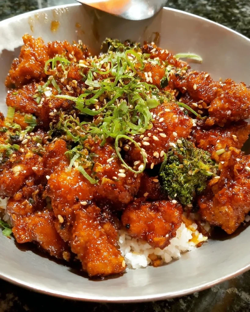 Crispy orange garlic chicken garnished with fresh herbs.