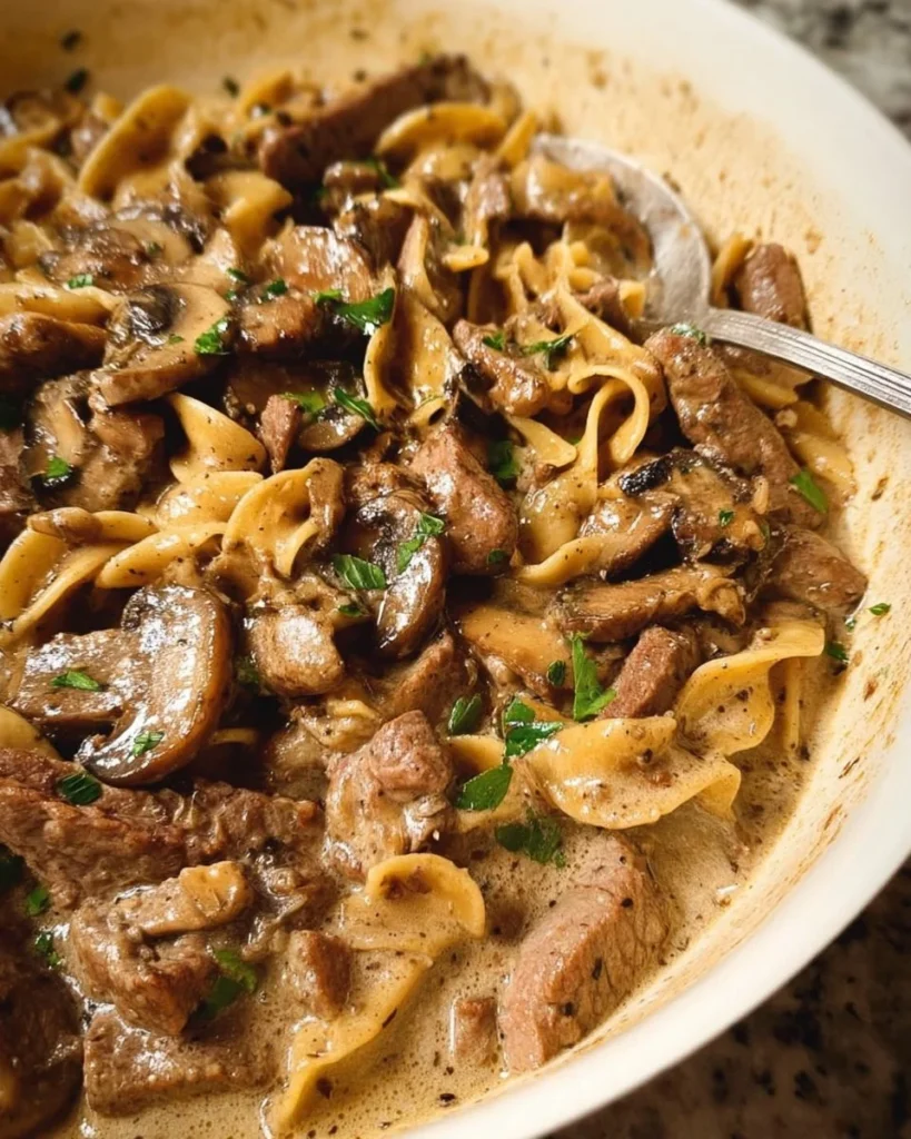 A creamy serving of easy beef stroganoff with mushrooms and noodles on a plate.