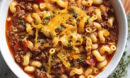 Delicious One-Pot American Goulash served in a bowl with cheese and herbs.
