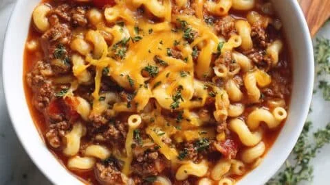 Delicious One-Pot American Goulash served in a bowl with cheese and herbs.