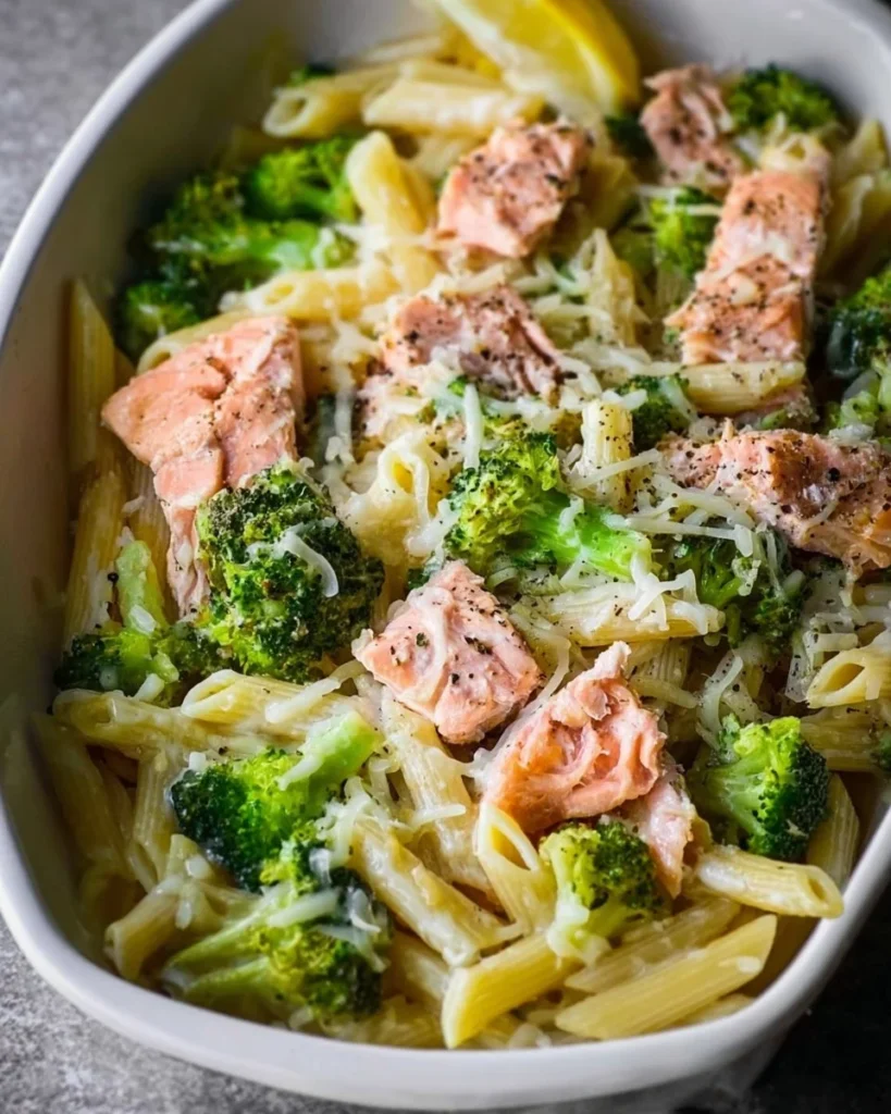 Plate of salmon broccoli pasta garnished with herbs