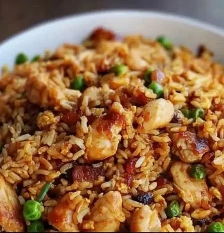 Bowl of savory BBQ chicken fried rice garnished with vegetables and sesame seeds