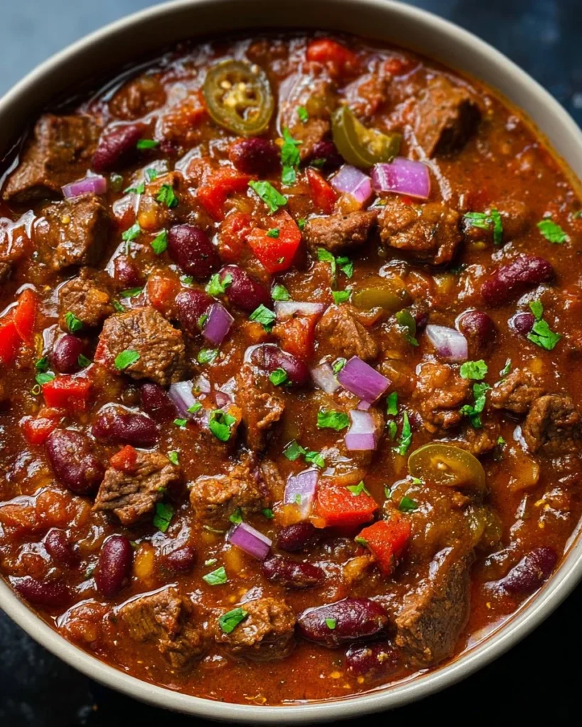 A delicious bowl of spicy steak chili garnished with fresh herbs