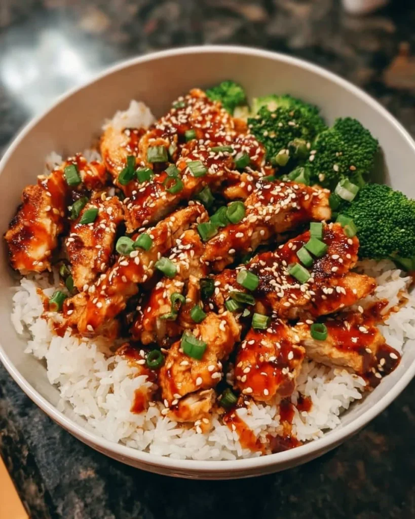 Sticky chicken rice bowl topped with vegetables and sauce
