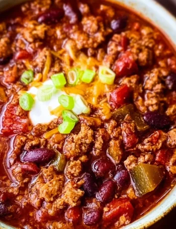 Bowl of ultimate crockpot chili topped with cheese and cilantro