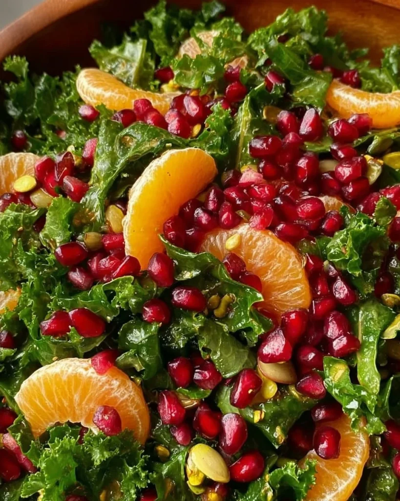 Citrus Pomegranate Kale Salad drizzled with Honey-Lemon Vinaigrette on a plate.