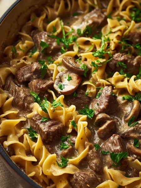 Delicious Dutch Oven Beef Stroganoff served with noodles and garnished with parsley.