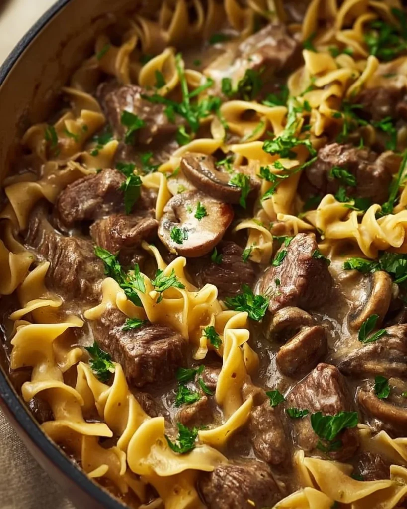 Delicious Dutch Oven Beef Stroganoff served with noodles and garnished with parsley.