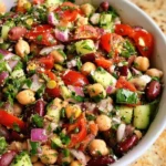 Bowl of colorful Mediterranean Bean Salad with fresh vegetables and herbs
