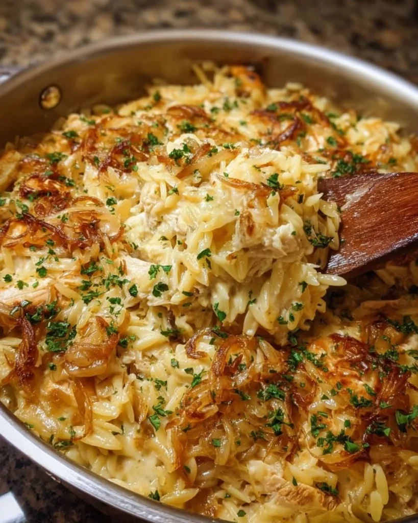 A delicious serving of French Onion Chicken Orzo Casserole topped with melted cheese.