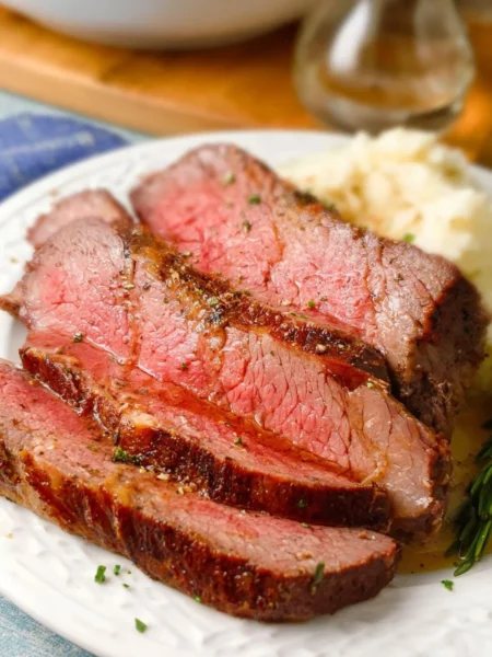 Juicy roast beef cooked in an air fryer, garnished and served on a plate.