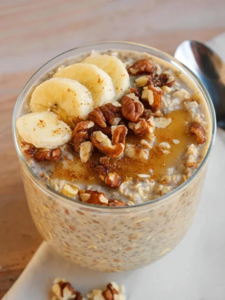 Delicious Banana Bread Overnight Oats in a glass with banana slices on top.