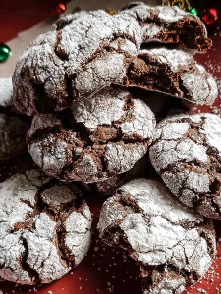 Gooey chocolate crinkle cookies dusted with powdered sugar on a plate.