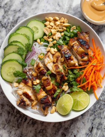 Grilled chicken spring roll bowl garnished with fresh vegetables and herbs