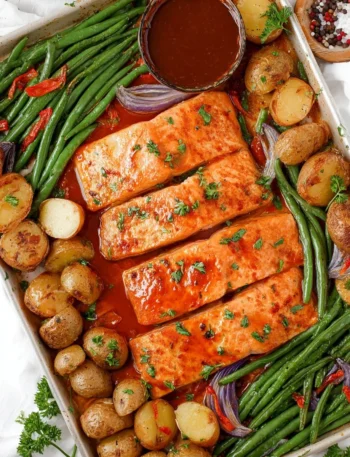 Maple glazed sheet pan salmon served with fresh vegetables on a baking tray.